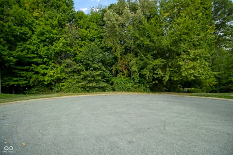 Front exterior at 13562 Creekridge Lane, Fishers, IN — Spacious circular driveway surrounded by mature trees.