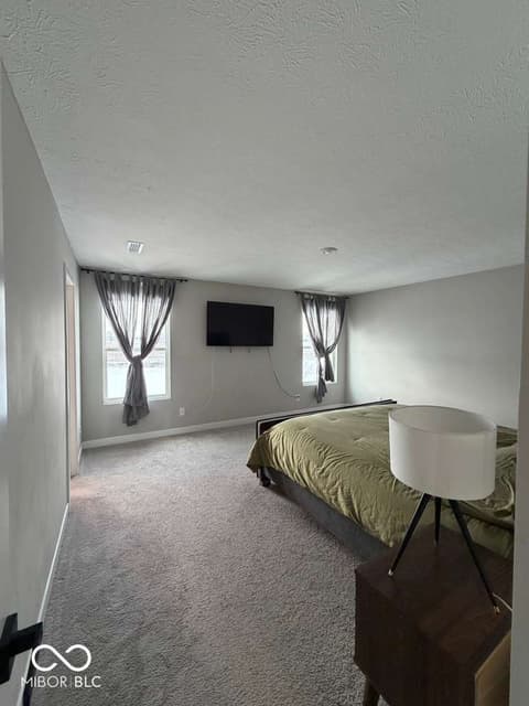 Bedroom at 19994 Edwick Drive, Westfield, IN — Spacious bedroom with dual windows and entertainment setup.