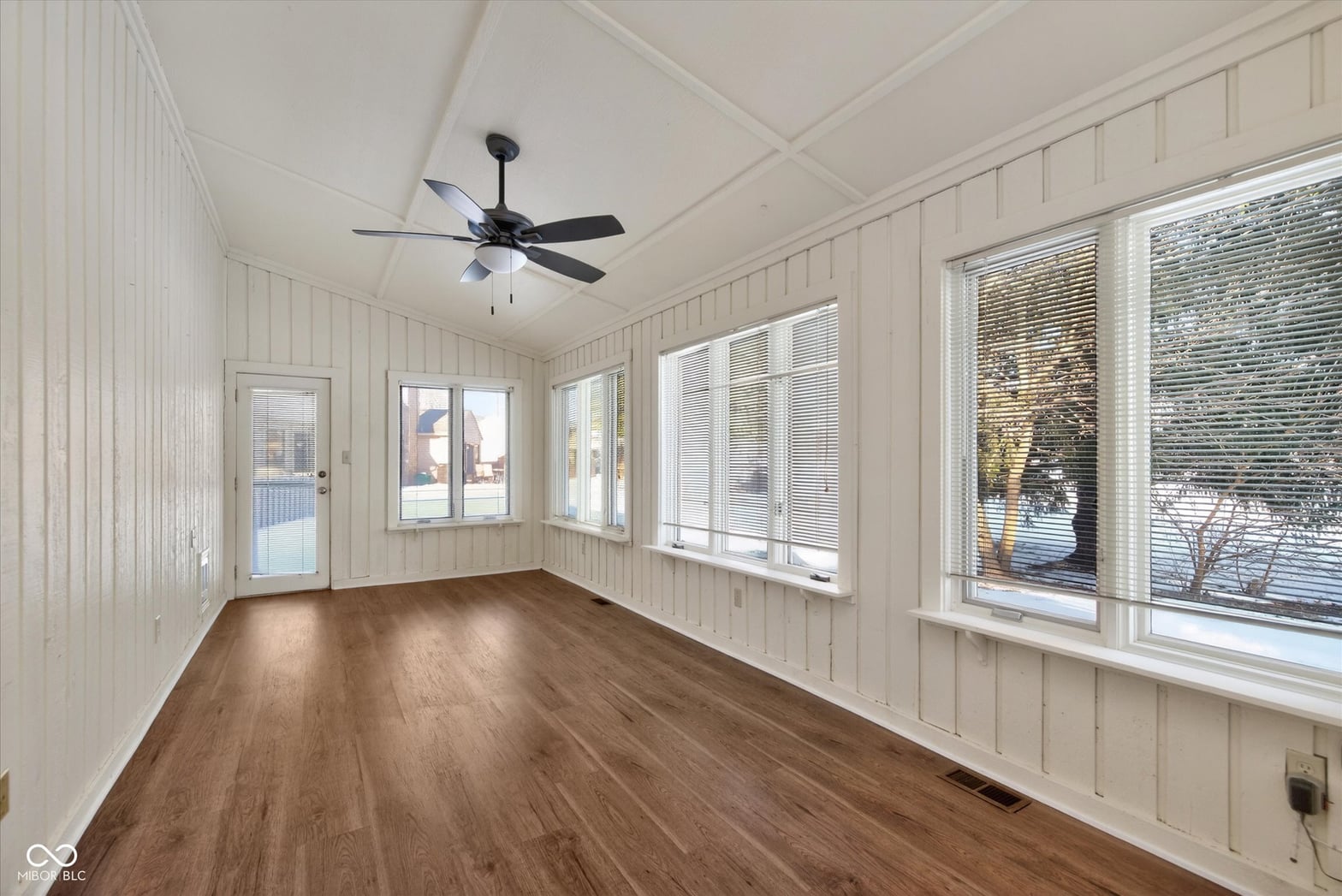 Bright screened porch with hardwood floors and abundant windows.