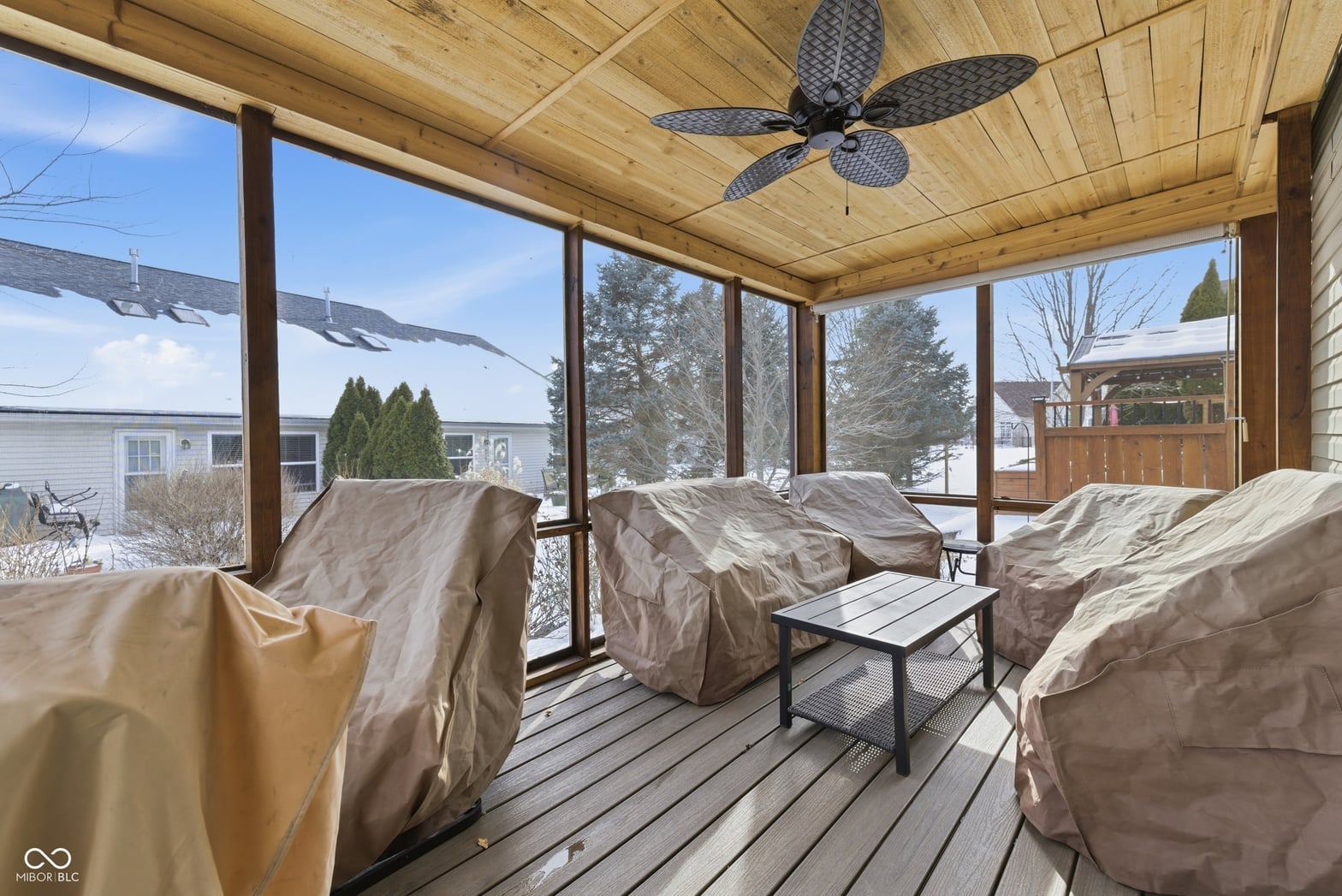 Expansive screened porch with wood ceiling and panoramic views.