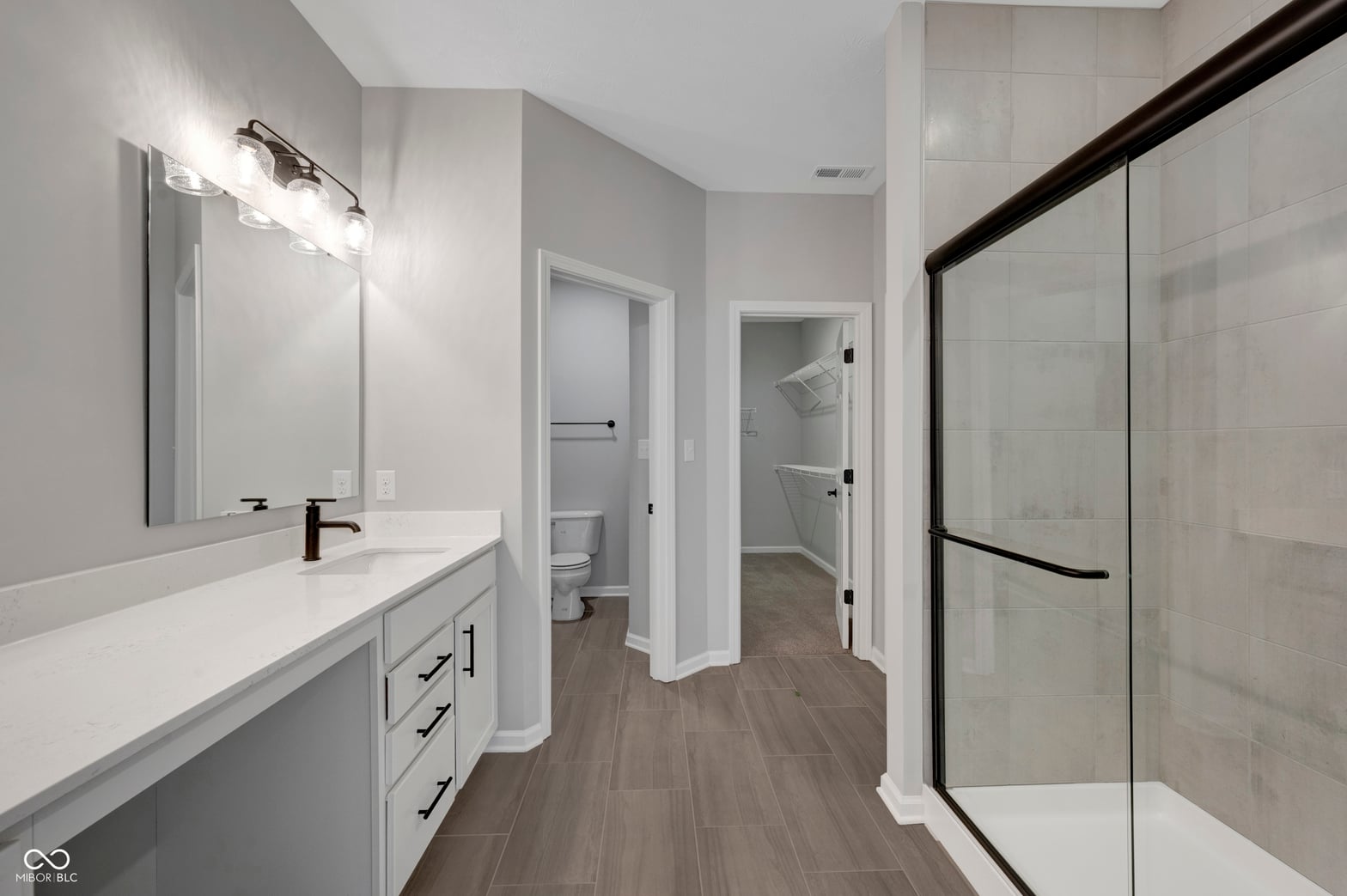 Luxurious primary bath with double vanity and glass shower.