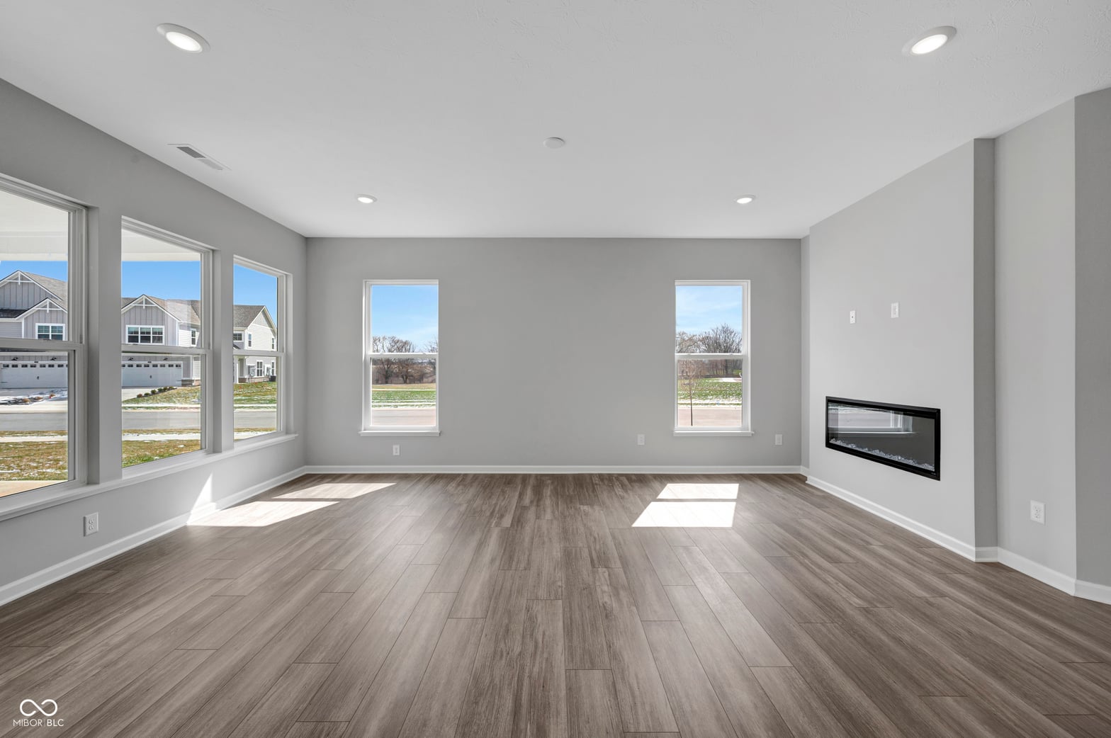 Bright, modern living room with abundant windows and fireplace.