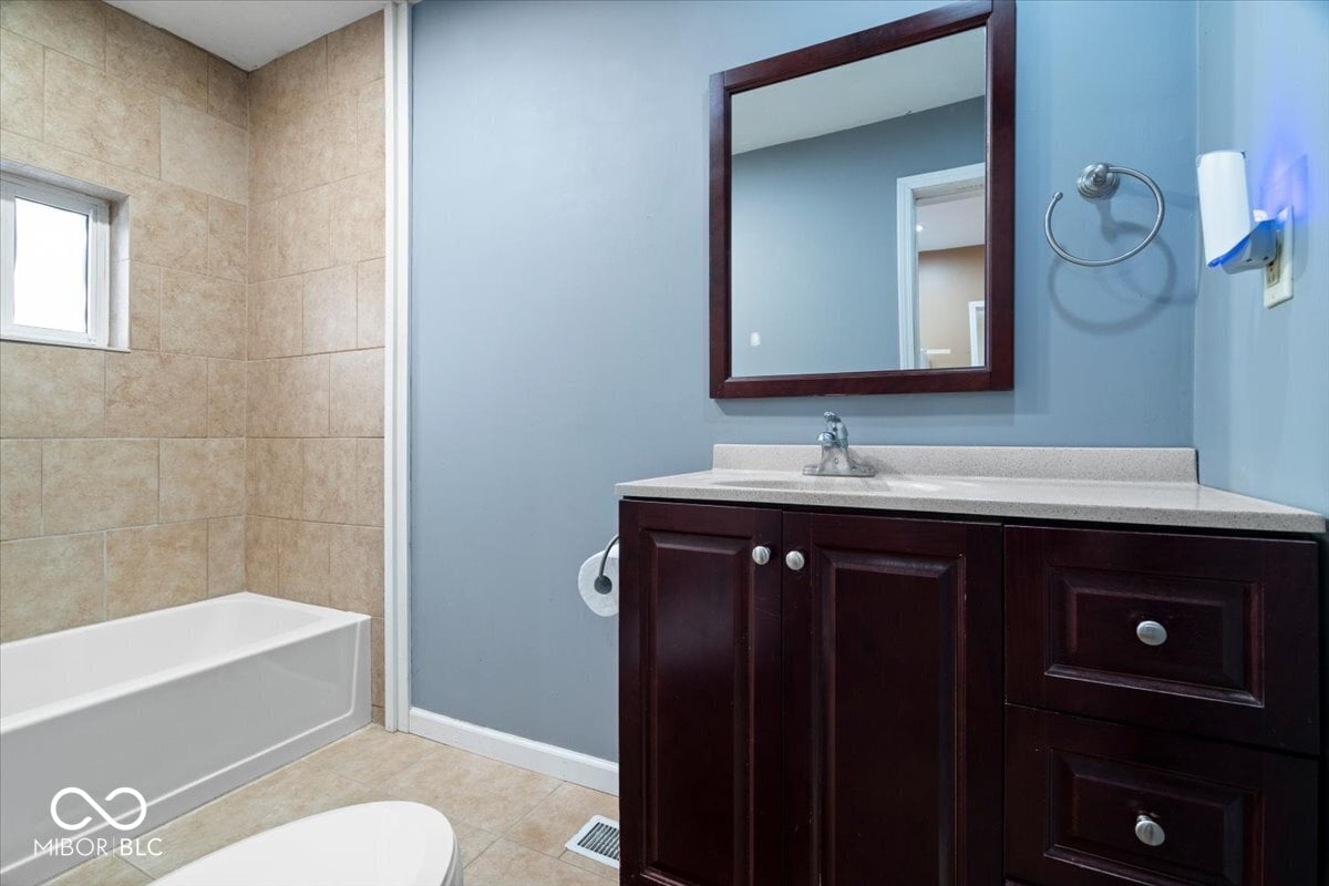 Updated primary bath with dark vanity and modern finishes.