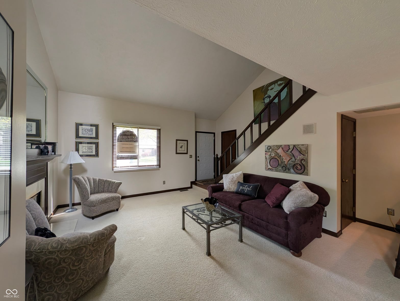 Open living space with vaulted ceilings and wood stairs.