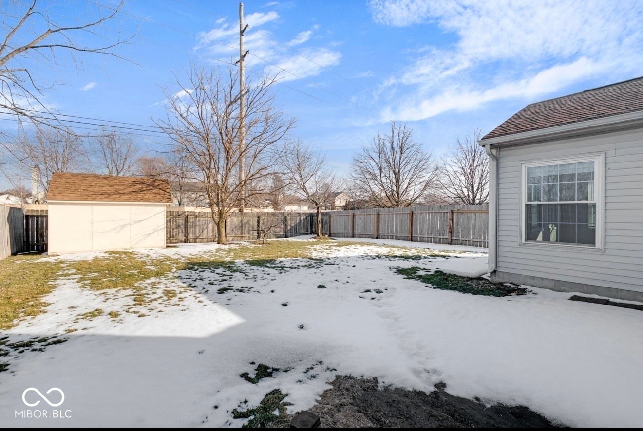 Large fenced backyard with mature trees and garage.