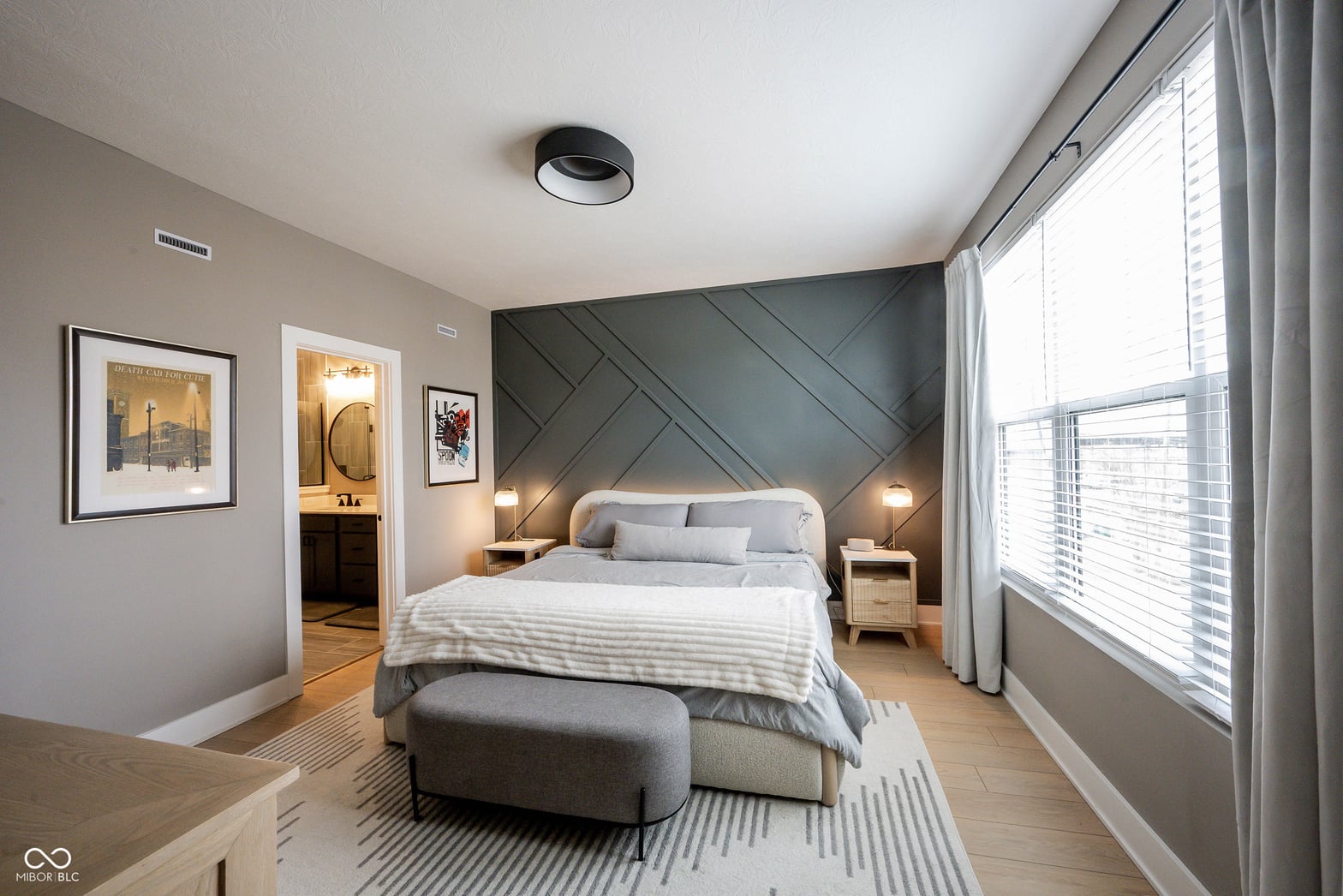 Modern primary bedroom with geometric accent wall and en-suite.