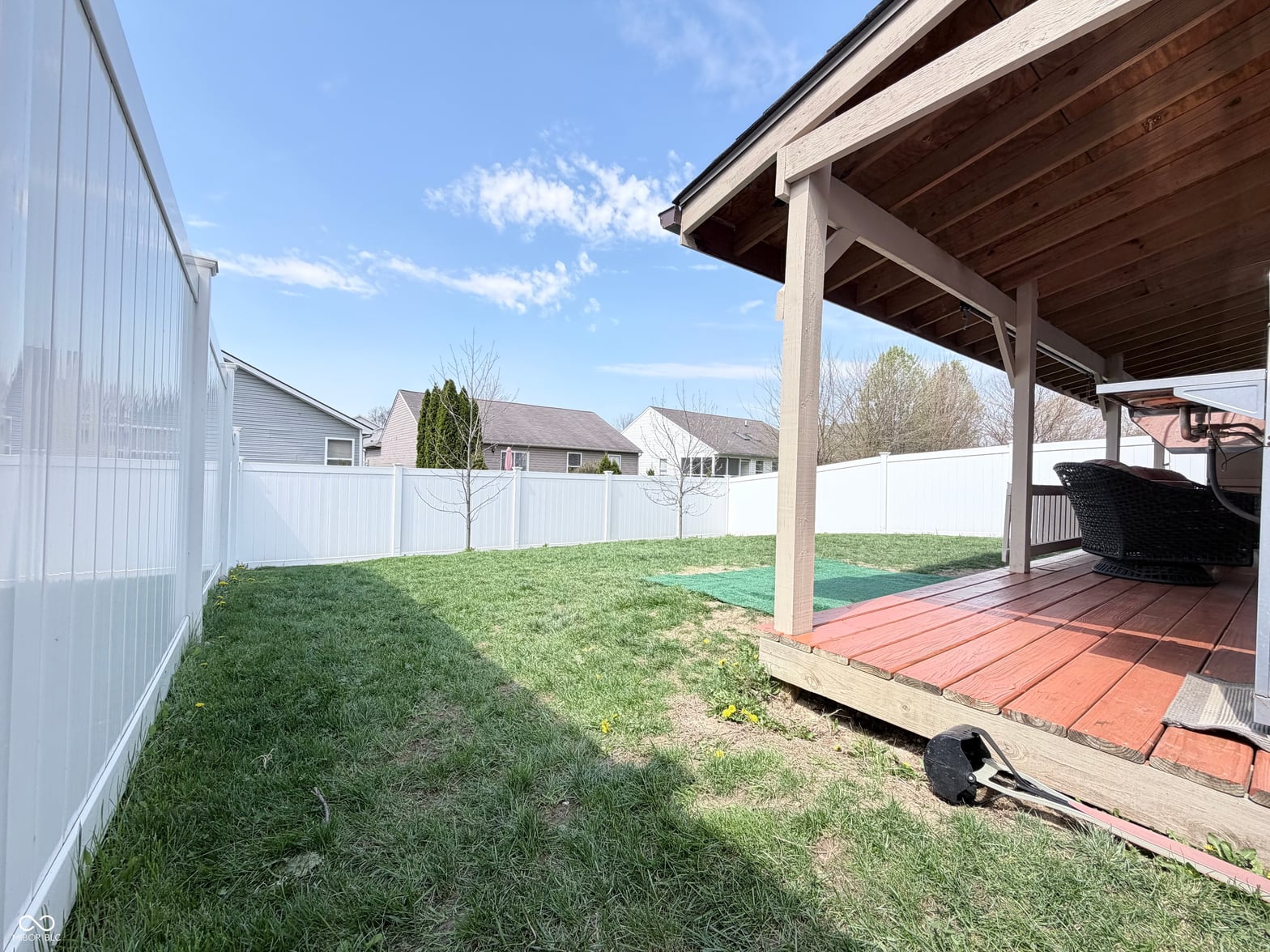 Spacious fenced backyard with covered patio and deck.