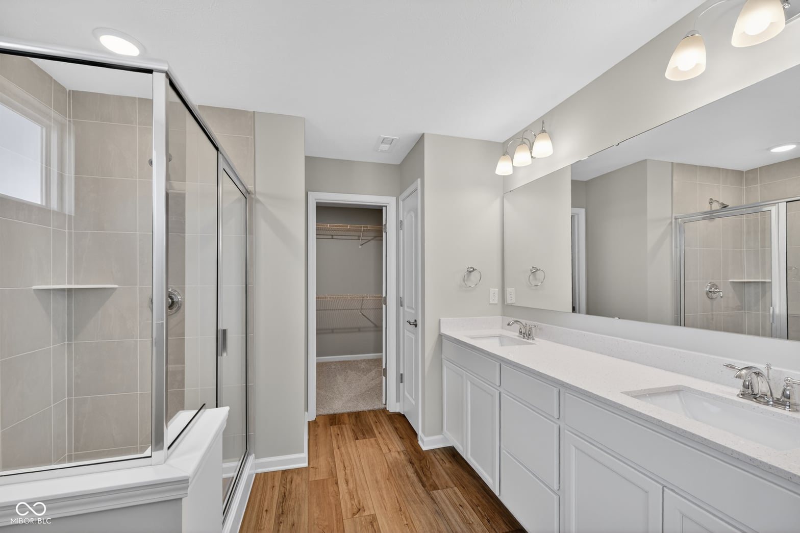 Luxurious primary bathroom with dual vanities and frameless shower.