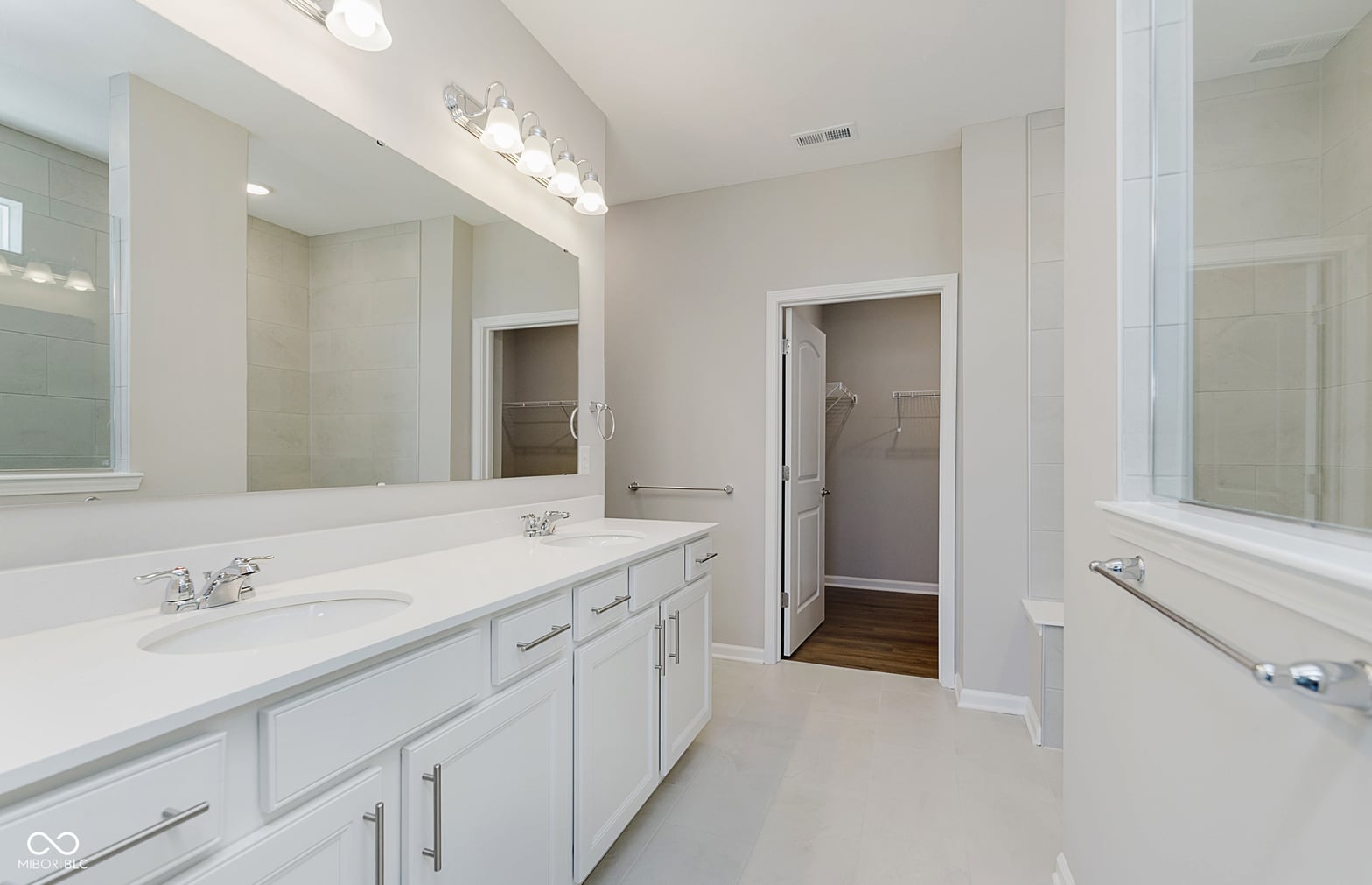 Luxurious primary bath with dual vanities and frameless shower.