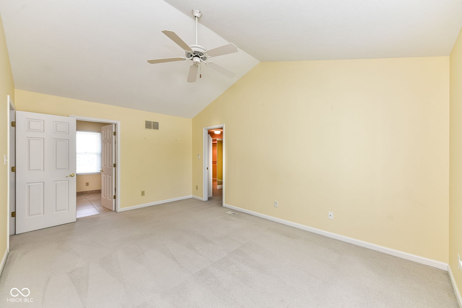 Spacious primary bedroom with vaulted ceilings and walk-in closet.