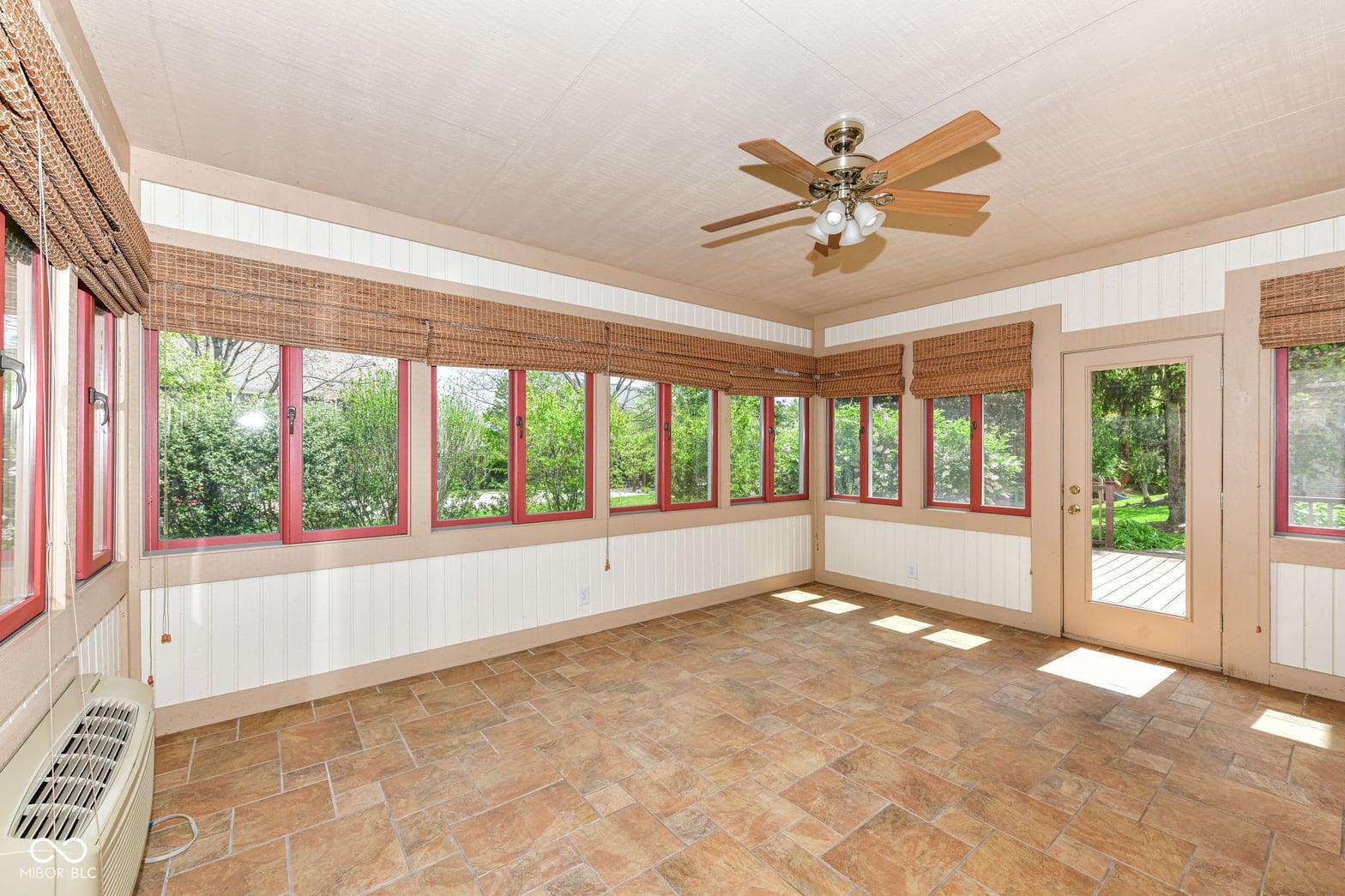Bright enclosed sunroom with extensive windows and doors.