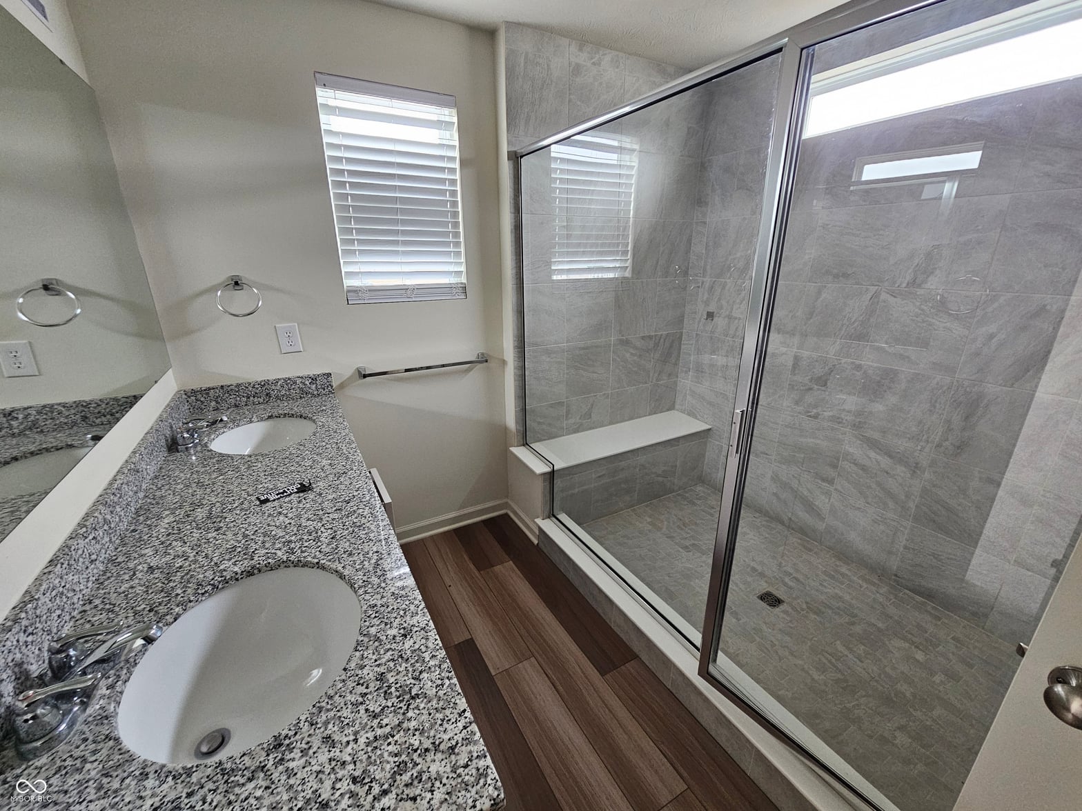 Spa-like primary bath with granite double vanity and walk-in shower.