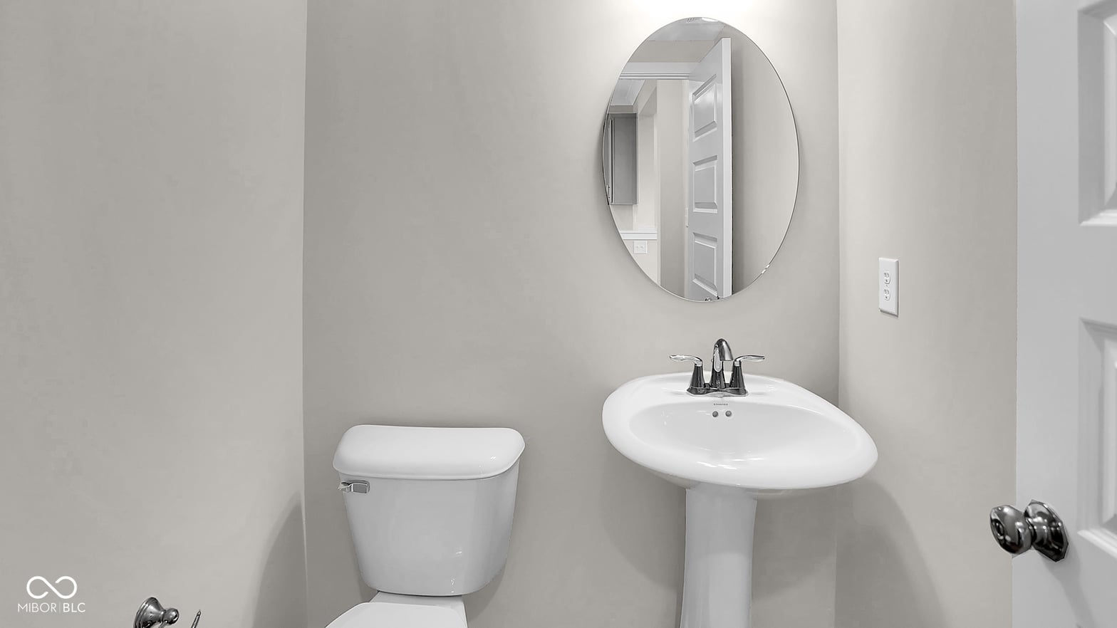 Bright, modern bathroom with pedestal sink and oval mirror.