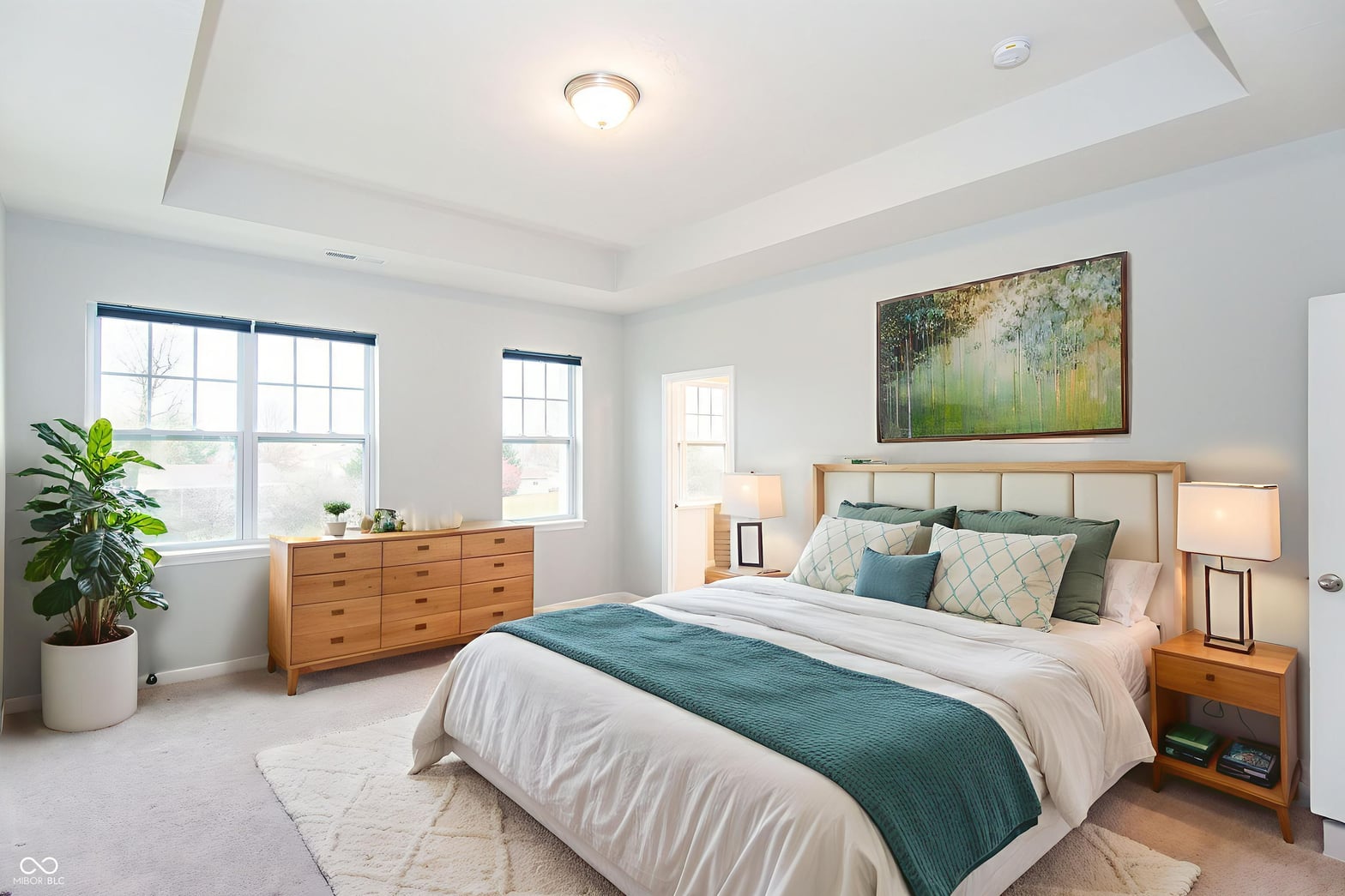 Bright primary bedroom with tray ceiling and abundant natural light.