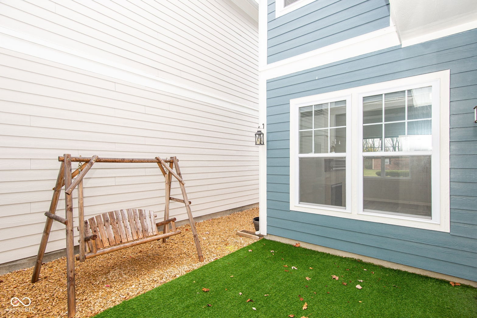 Modern backyard with artificial turf and charming swing.
