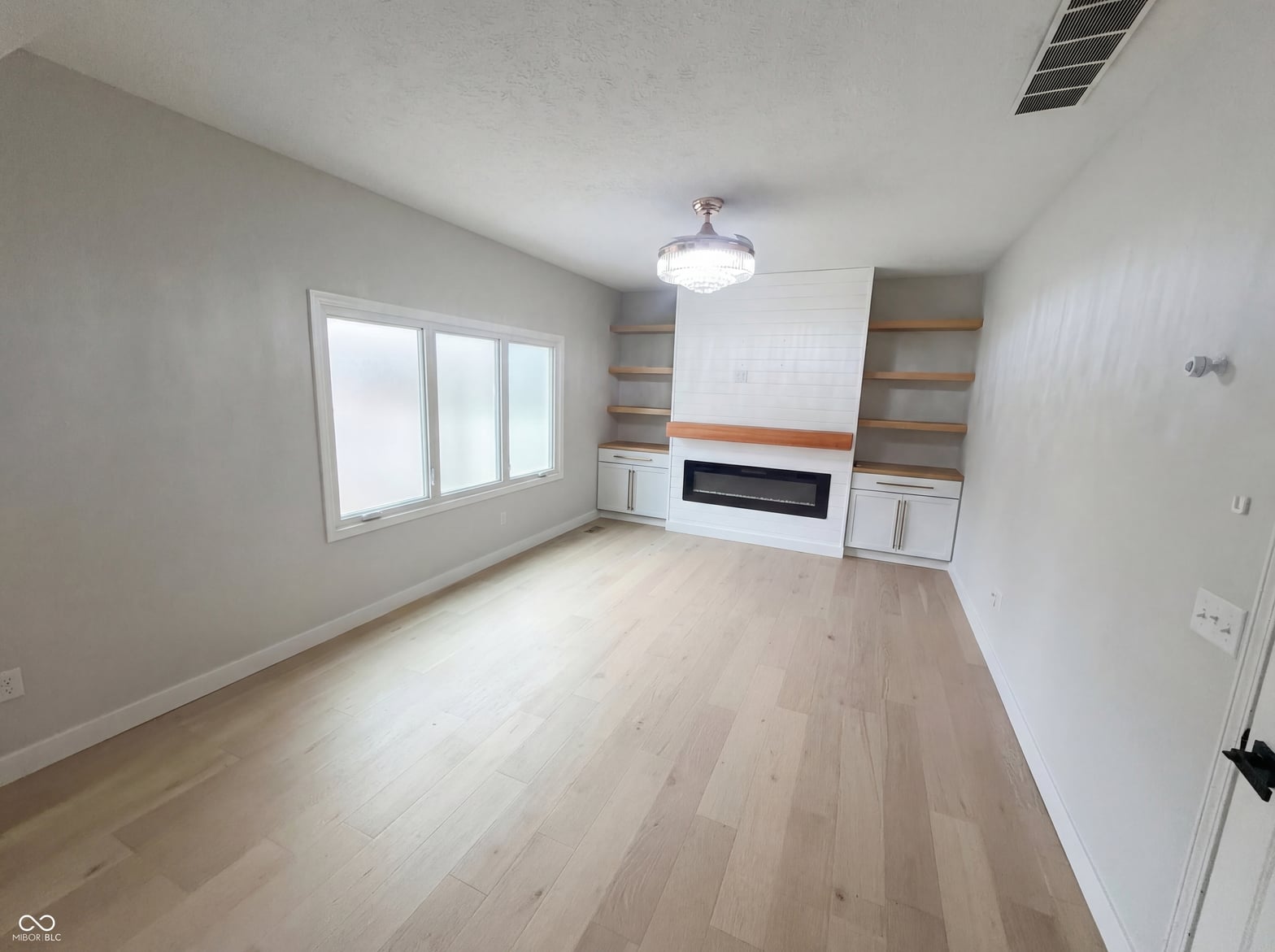 Modern family room with sleek fireplace and built-in shelving.