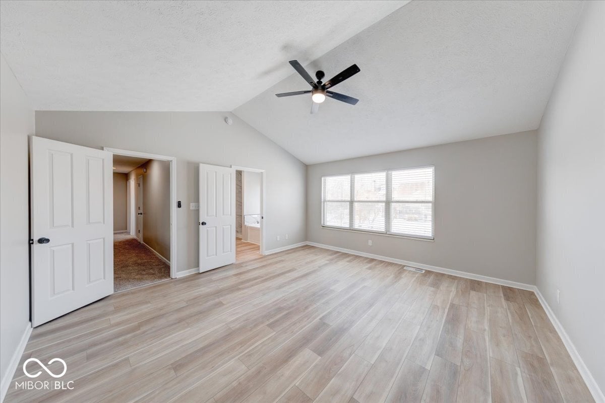 Spacious primary bedroom with vaulted ceiling and natural light.