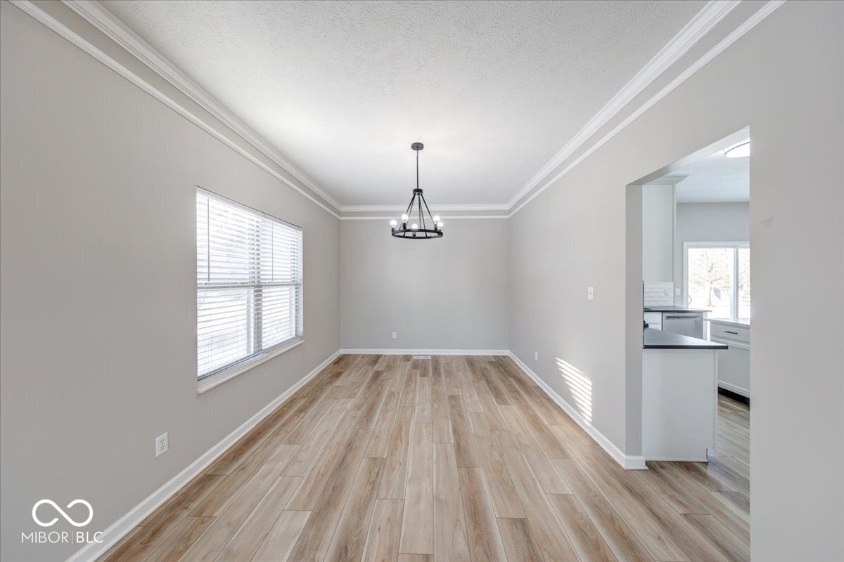 Bright open dining area with hardwood floors and crown molding.