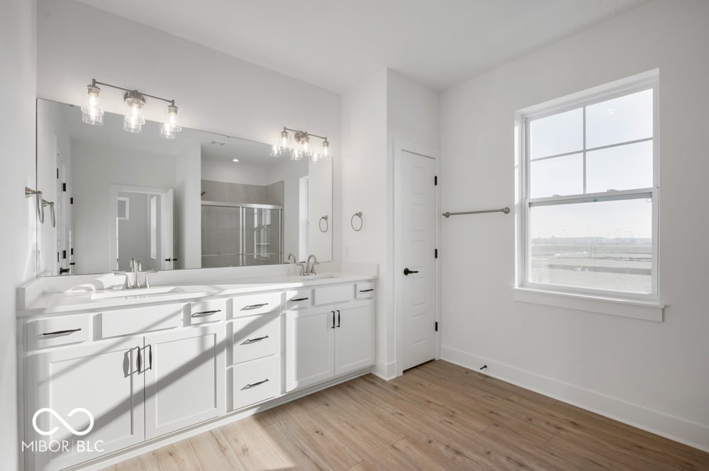 Luxurious modern primary bath with double vanity and spa shower.