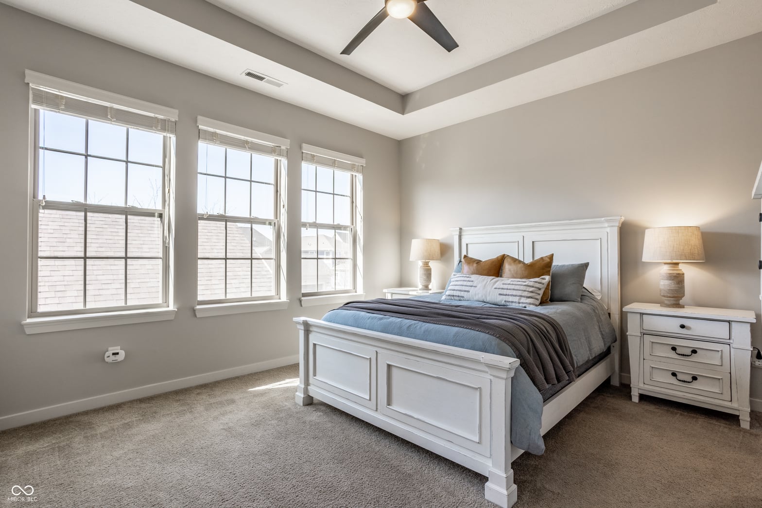 Bright primary bedroom with coffered ceiling and abundant windows.