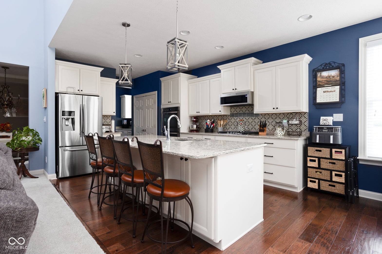 Modern kitchen with island, granite counters, and navy accent walls.