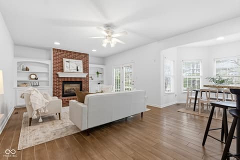 Living room at 13867 Smokey Ridge Drive, Carmel, IN — Bright living room with brick fireplace and built-ins.