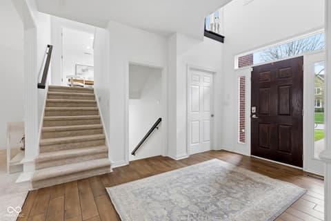 Foyer at 13867 Smokey Ridge Drive, Carmel, IN — Bright foyer with hardwood floors and carpeted staircase.
