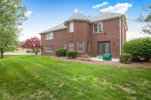 Backyard at 13867 Smokey Ridge Drive, Carmel, IN — Spacious brick home with manicured grounds and mature trees.
