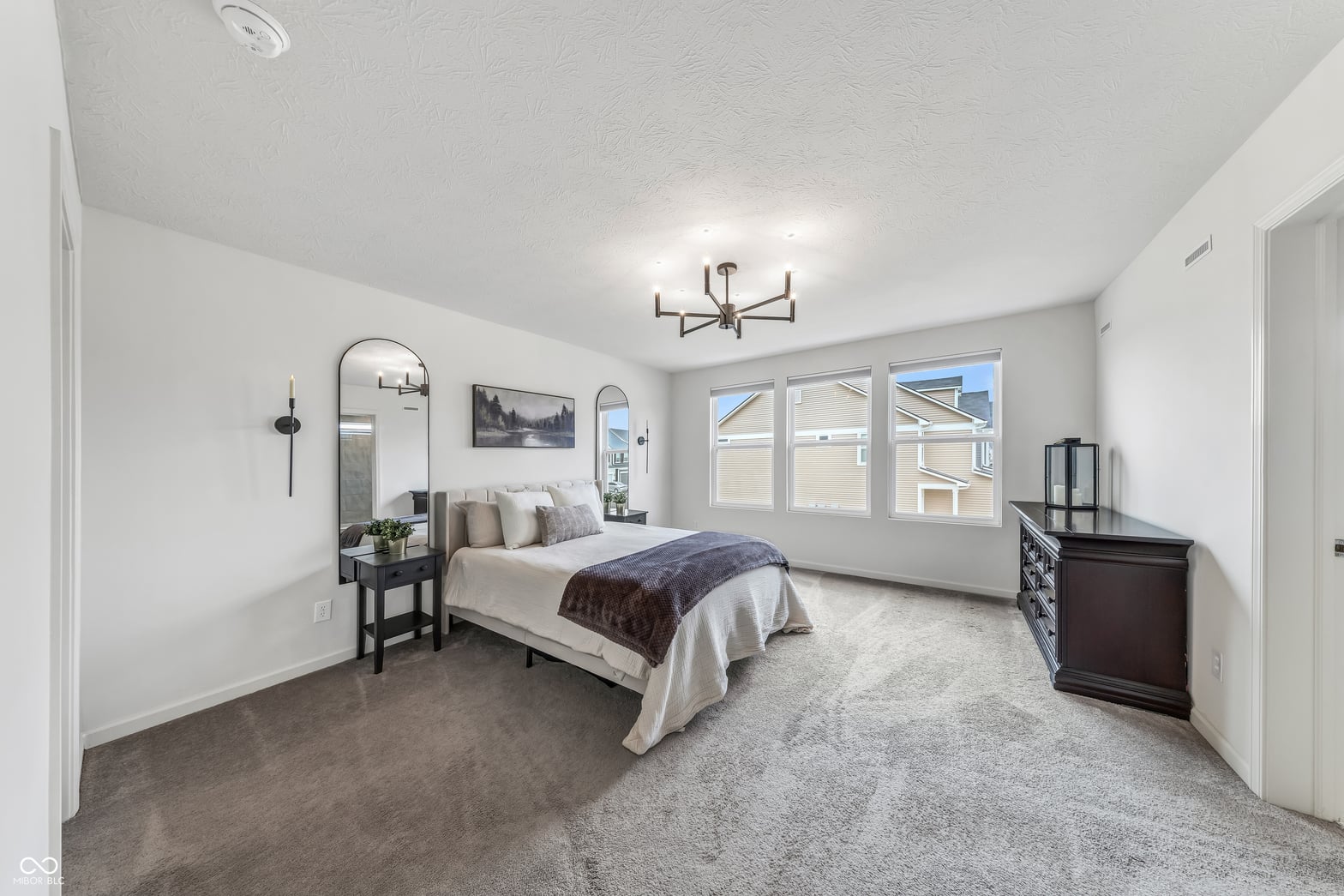 Bright primary bedroom with abundant windows and modern finishes.