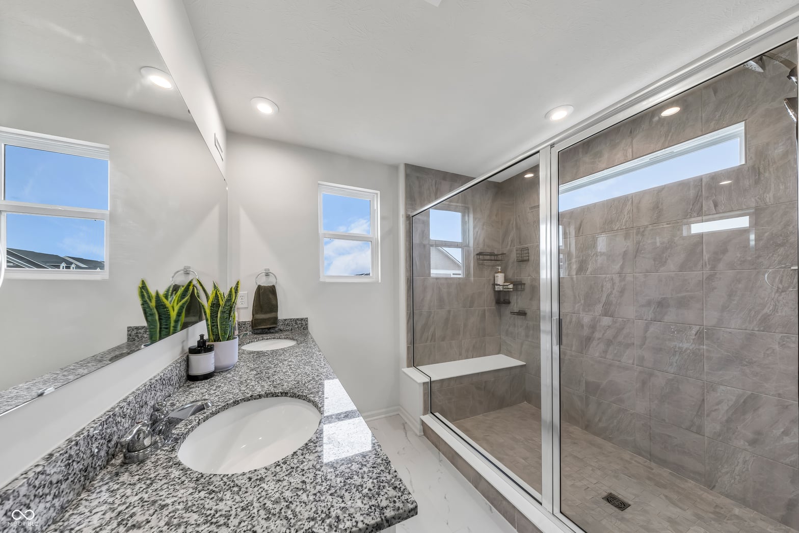 Luxurious primary bath with granite counters and frameless shower.
