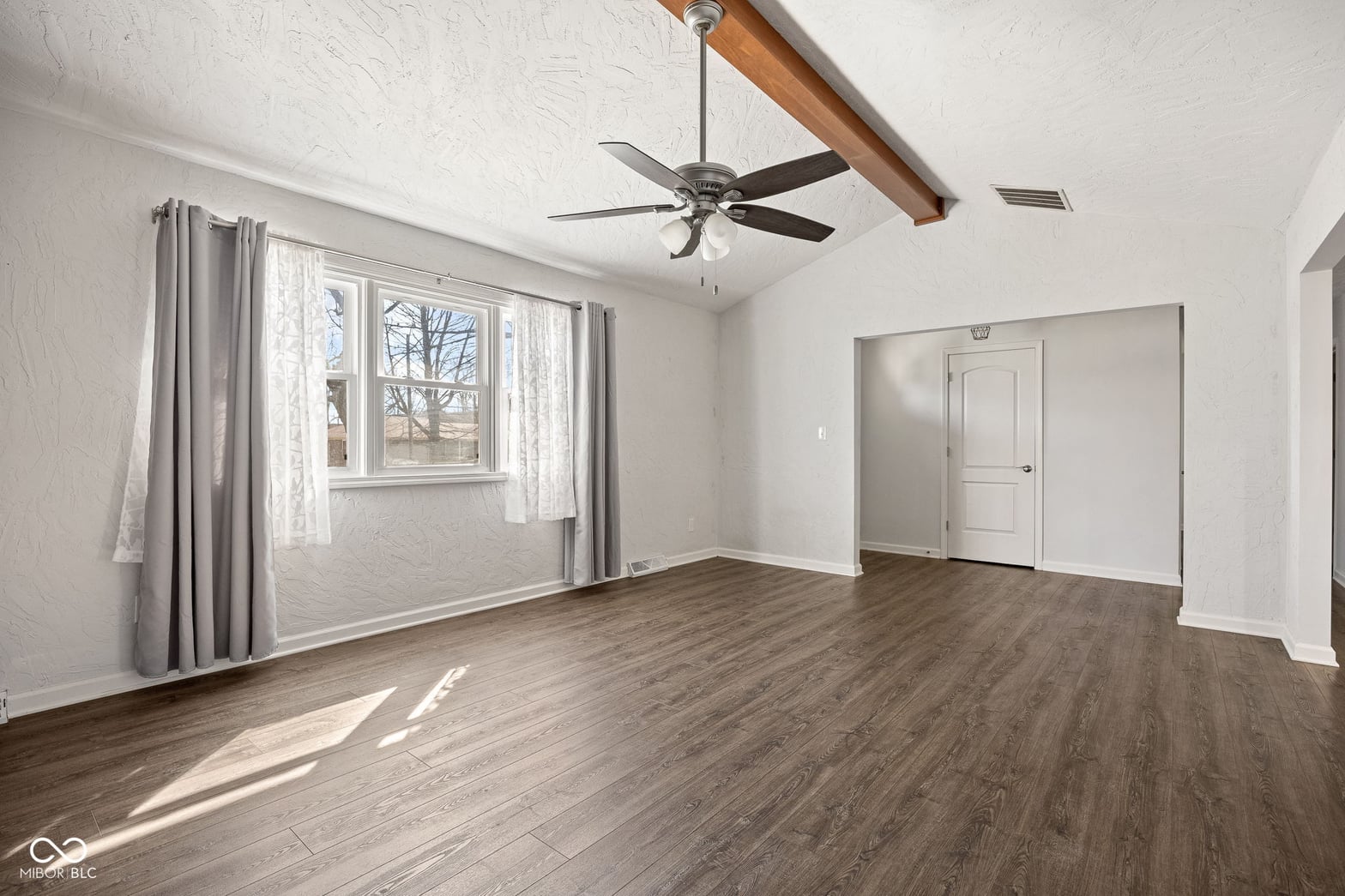 Spacious primary bedroom with hardwood floors and natural light.