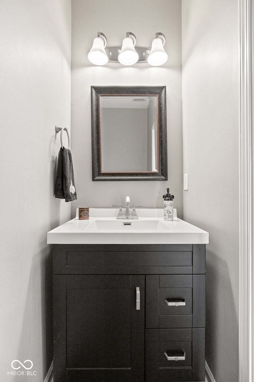 Modern bathroom with sleek dark vanity and bright lighting.