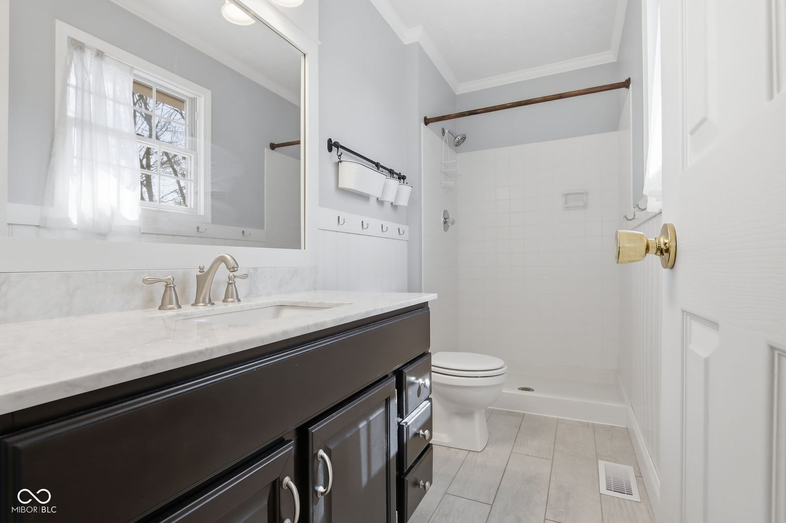 Bright renovated primary bath with marble counters and modern fixtures.