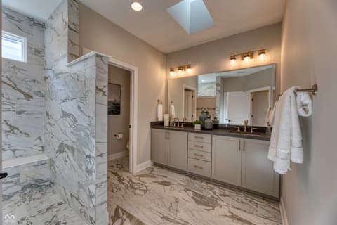 Primary bathroom at 5918 Maple Glen Drive, Noblesville, IN — Luxurious primary bath with marble finishes and skylight.