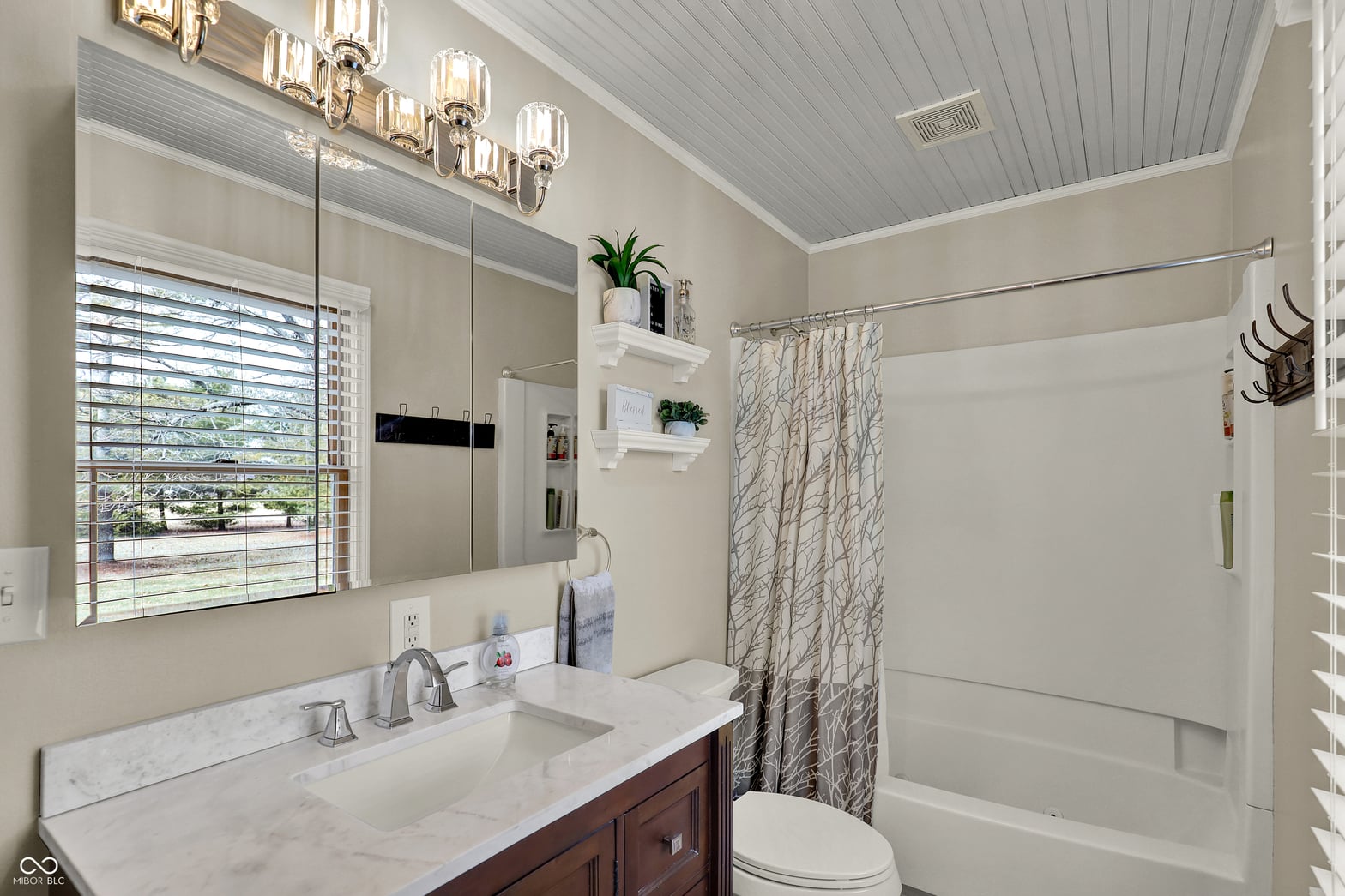 Bright renovated primary bath with marble and modern fixtures.
