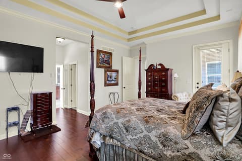 Primary bedroom at 10001 Copper Saddle Bend, Fishers, IN — Elegant primary suite with tray ceiling and hardwood floors.