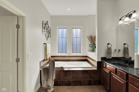 Primary bathroom at 10001 Copper Saddle Bend, Fishers, IN — Luxurious primary bath with soaking tub and dual vanity.