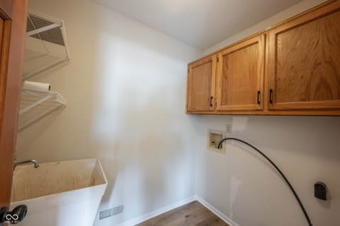Laundry room at 72 Ashbourne Drive, Noblesville, IN — Functional laundry room with oak cabinets and utility sink.