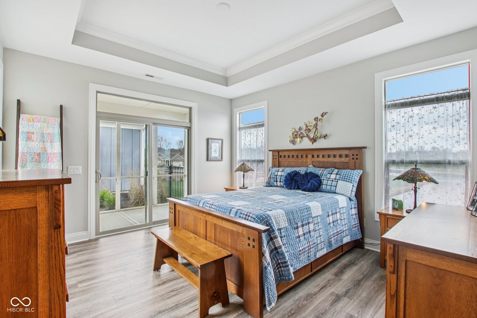 Bright primary bedroom with coffered ceilings and water views.