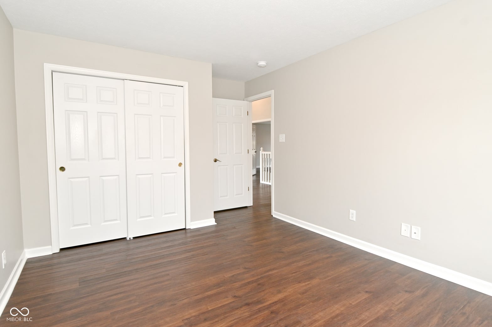 Spacious primary bedroom with hardwood floors and ample closet storage.