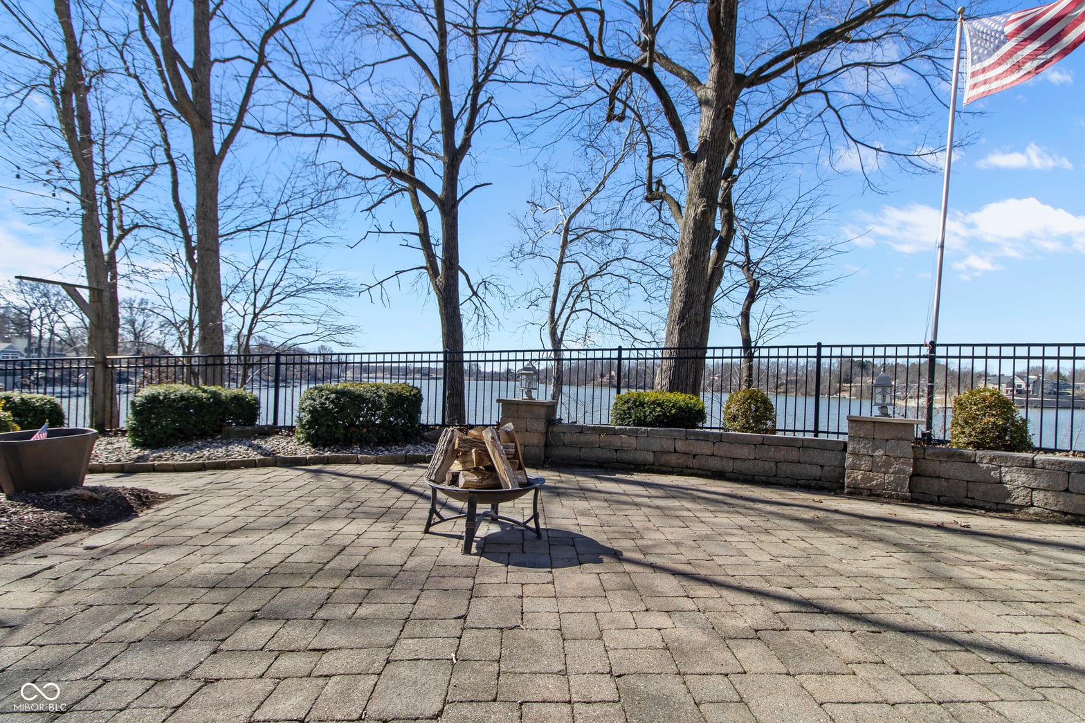 Expansive paved patio with scenic water views and fireplace.