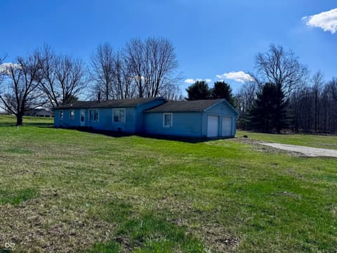 Front exterior at 3231 W State Road 32, Westfield, IN — Rural mobile home with attached garage on expansive grounds.