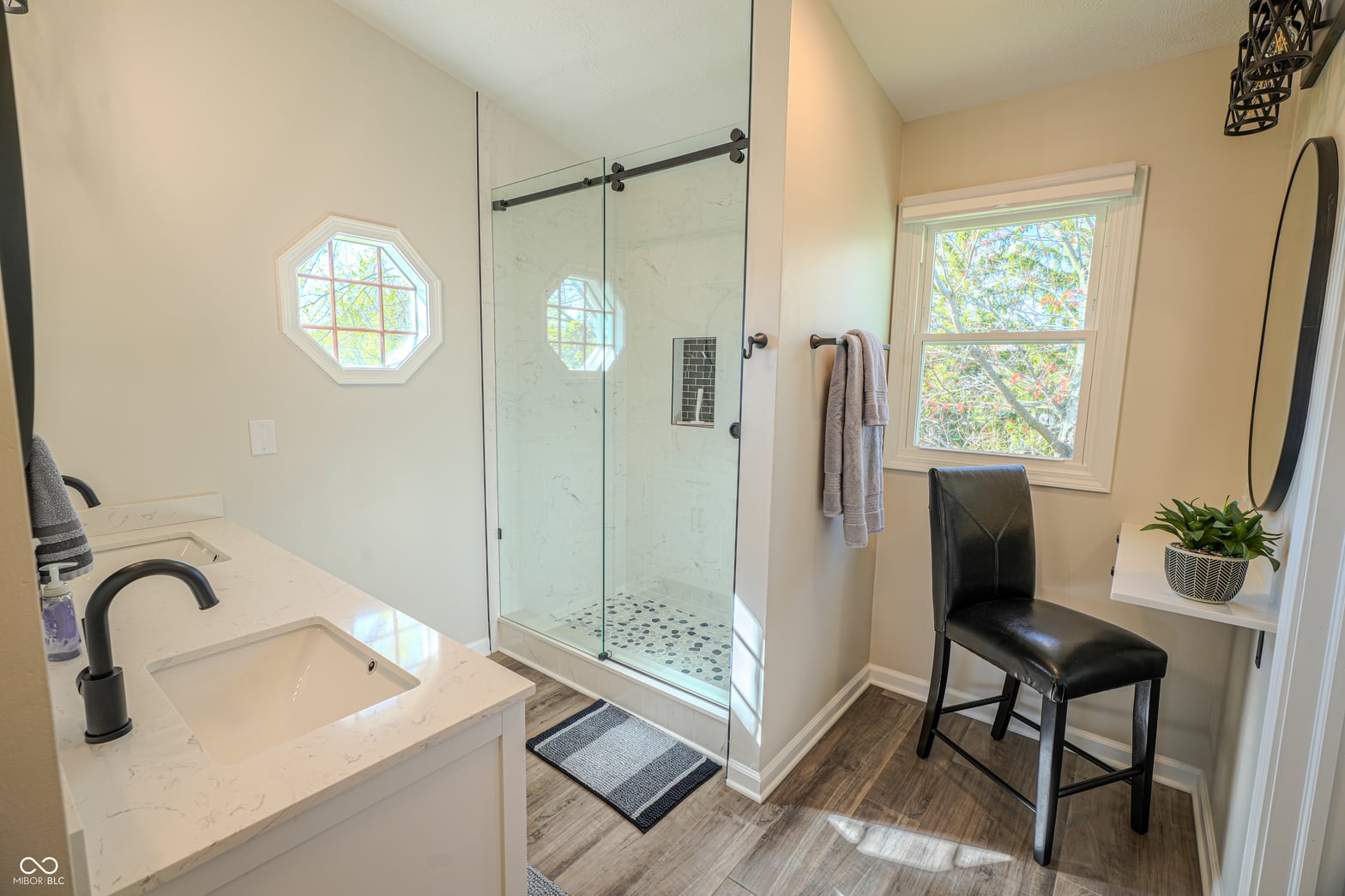 Luxurious primary bath with frameless shower and marble counters.