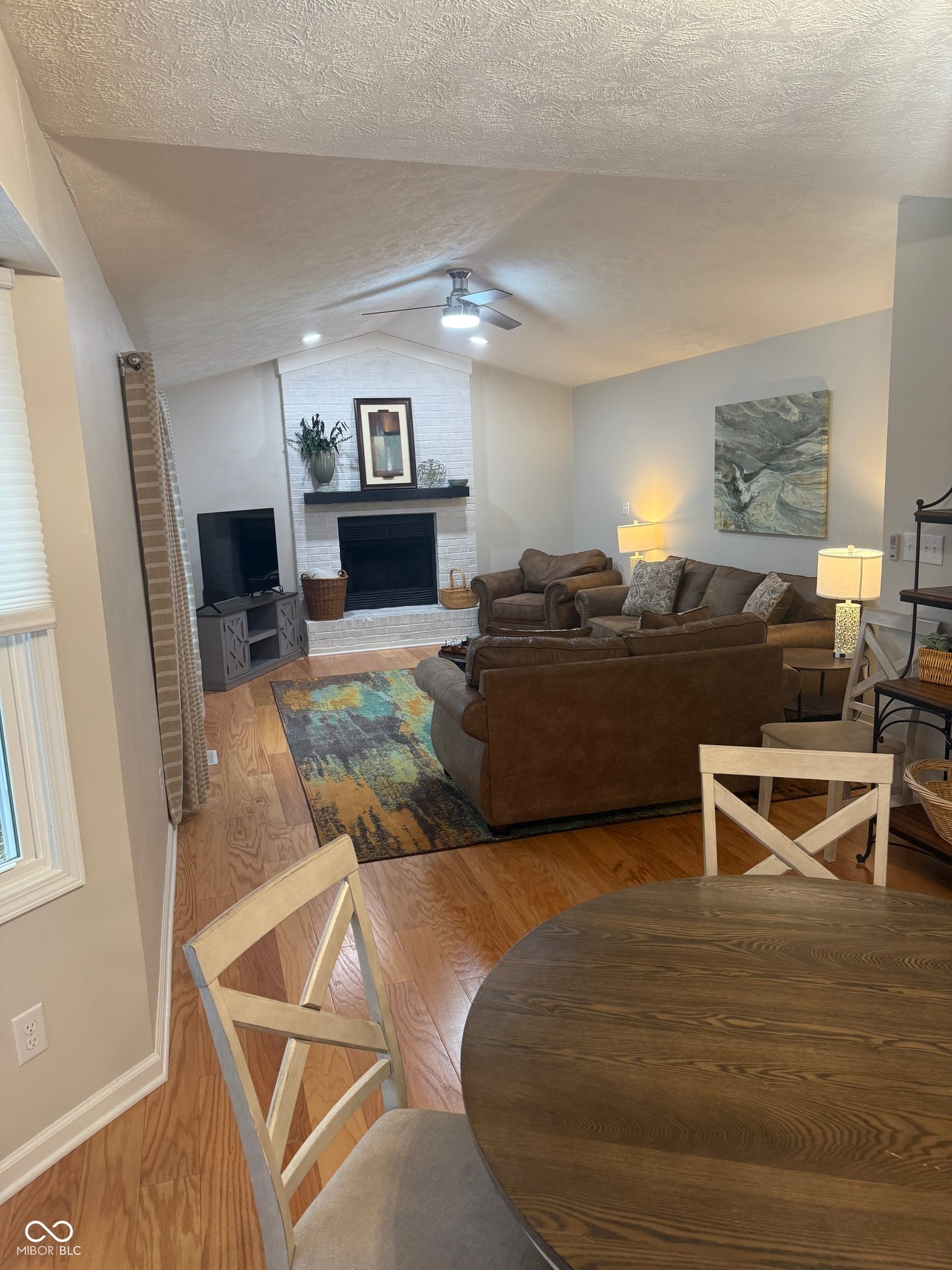 Bright open living space with fireplace and vaulted ceilings.