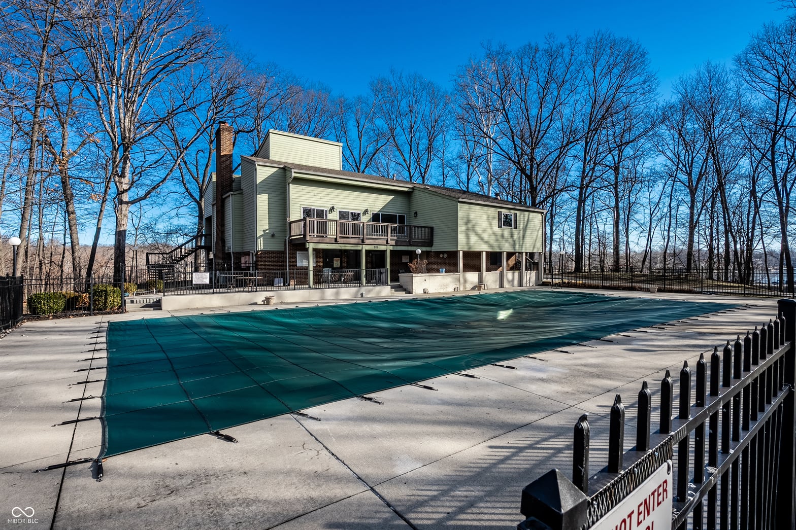 Resort-style pool with fenced privacy in wooded setting.