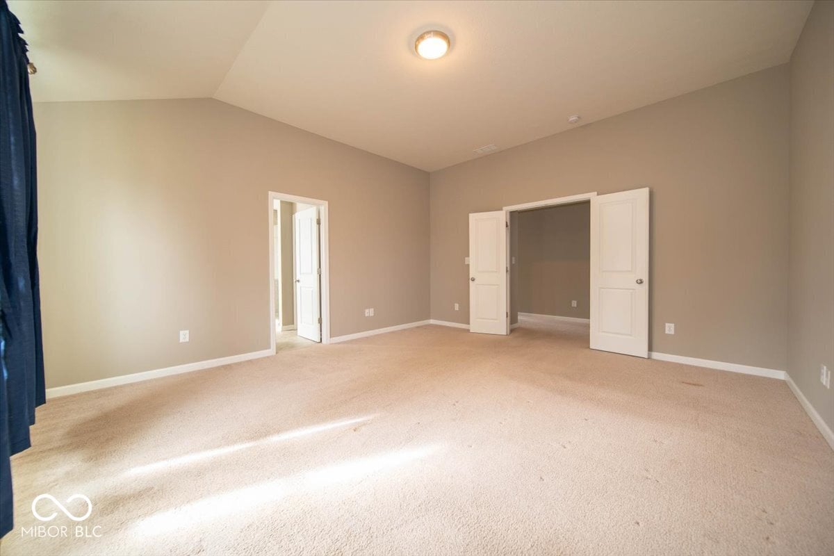 Spacious primary bedroom with dual closets and neutral finishes.
