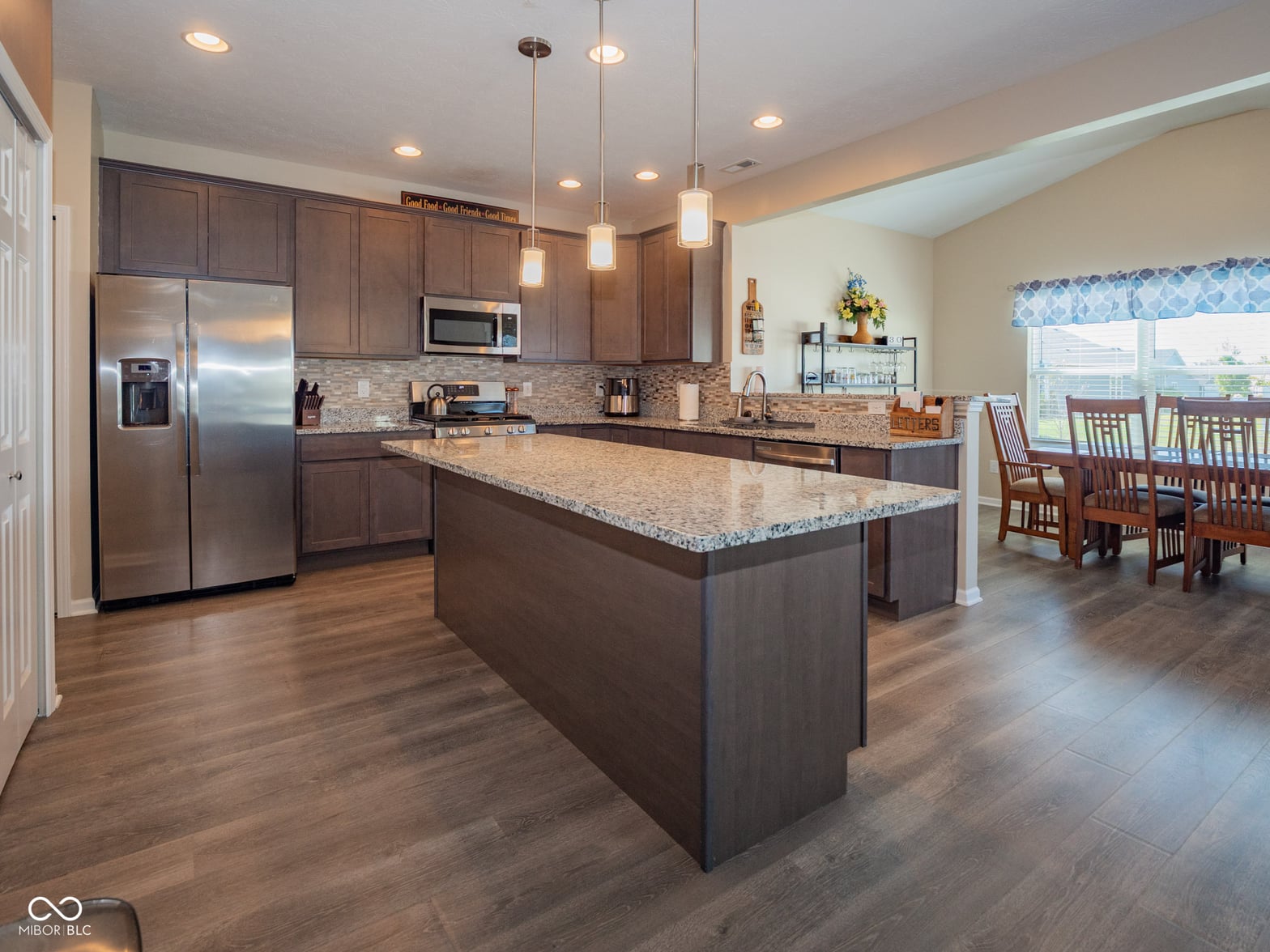 Spacious kitchen with granite island and stainless appliances.