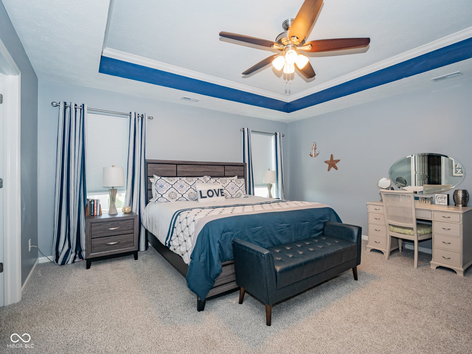 Spacious primary bedroom with stylish accent ceiling and modern furnishings.