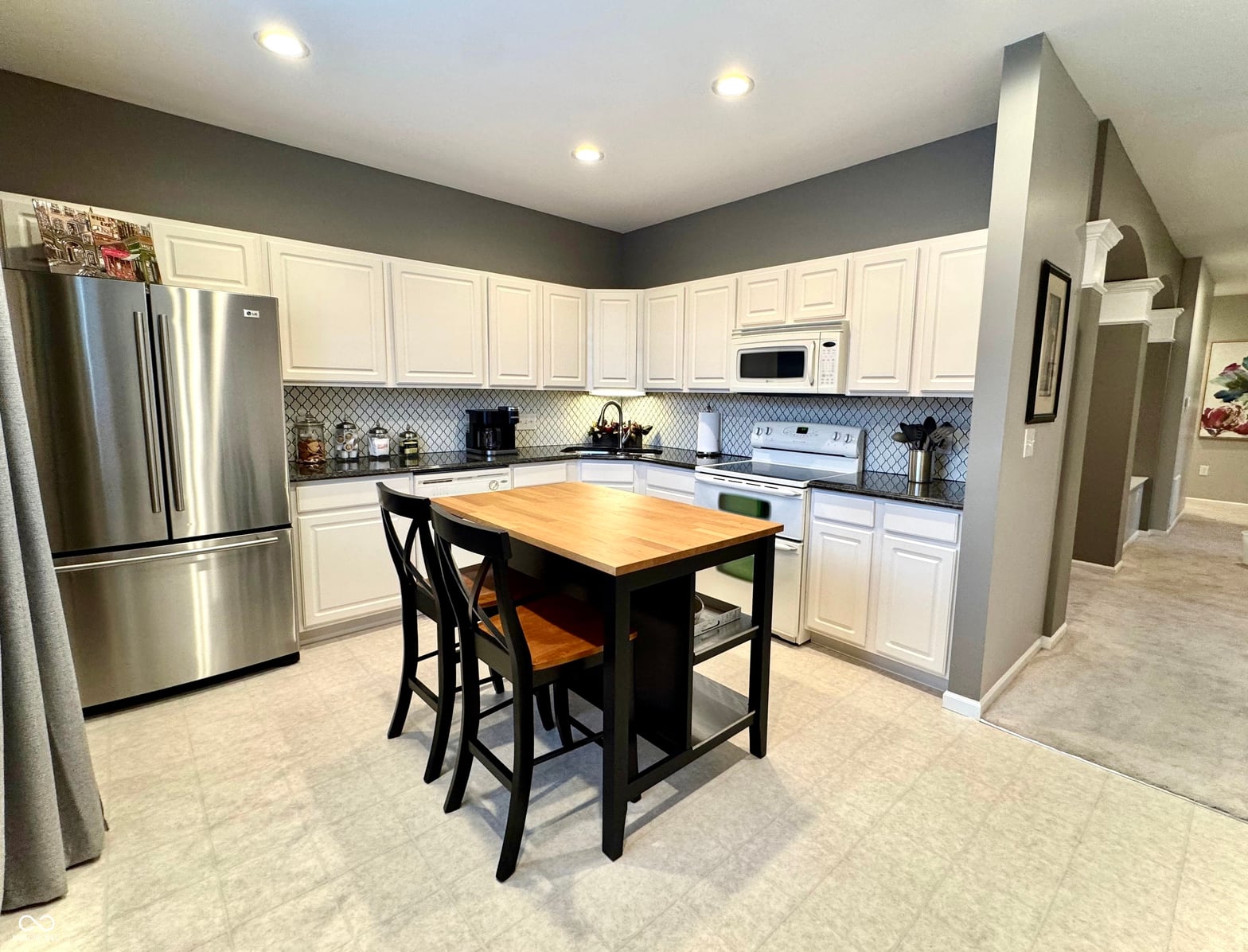 Updated kitchen with island seating and stainless steel appliances.