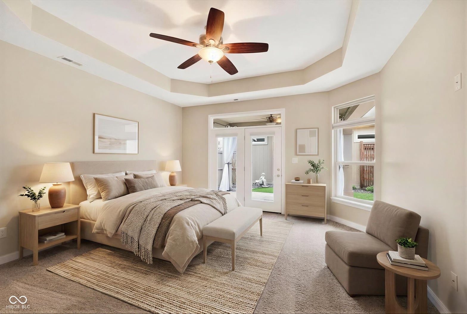 Spacious primary suite with tray ceiling and patio access.